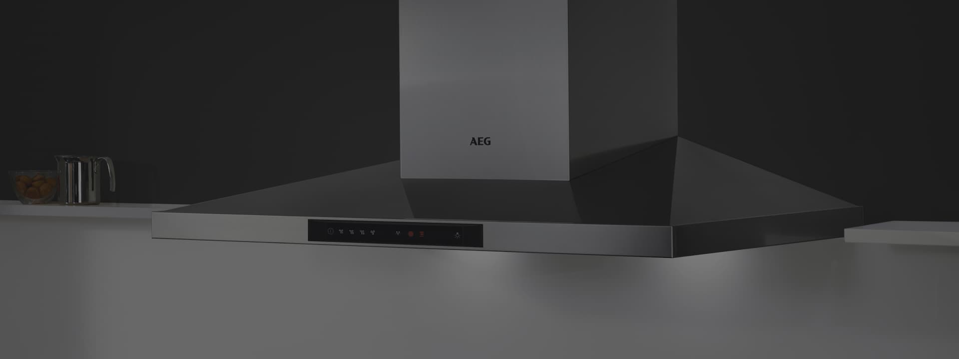 Een keuken met een zwarte wand waar een AEG wandafzuigkap aan hangt die aan staat.